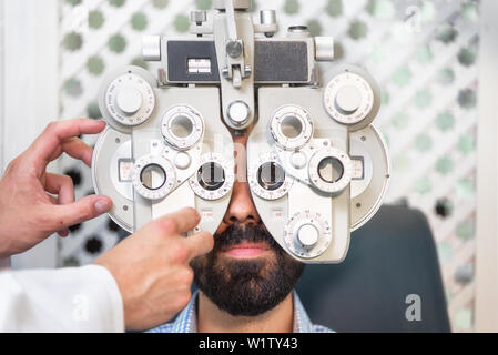 All'ottico optometrista vista facendo il test per paziente di sesso maschile in clinica. Oculista maschio esame paziente uomo con all'ottico optometrista telaio di prova . Foto Stock