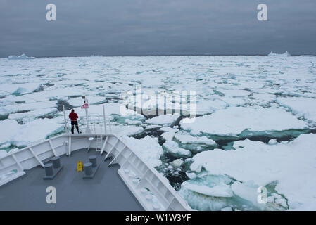 Una persona solitaria sorge sulla cosiddetta 'Monkey " Ponte della Expedition nave da crociera MS Bremen (Hapag-Lloyd crociere) immerso in una massa di ghiaccio marino, vicino a Lau Foto Stock