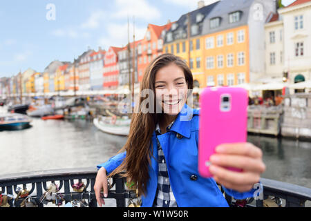 Asian tourist donna prendendo selfie a Copenhagen Nyhavn. Famoso punto di riferimento, Nord Europa destinazione, la old town waterfront canale d'acqua nella capitale Kobenhavn in Danimarca e Scandinavia. Foto Stock