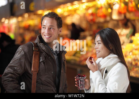 Barcellona La Boqueria street market turisti giovane sul loro viaggio in Europa, shopping Mangiare le ciliege fresche acquistate dal cibo stallo. Giovani gruppo multietnico di persone. Foto Stock