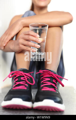 Atleta Fitness donna acqua potabile azienda vetro - lato closeup concetto di idratazione. Runner donna impedendo la disidratazione per la sua salute e il corpo. Foto Stock