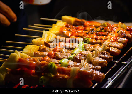 Barbecue grigliate di carne con verdure e salsa di pomodoro sulle griglie di acciaio con il calore. Foto Stock