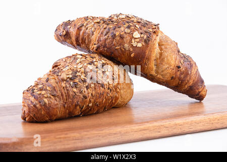 Una coppia di pane appena sfornato Croissant su un tagliere isolato su bianco Foto Stock