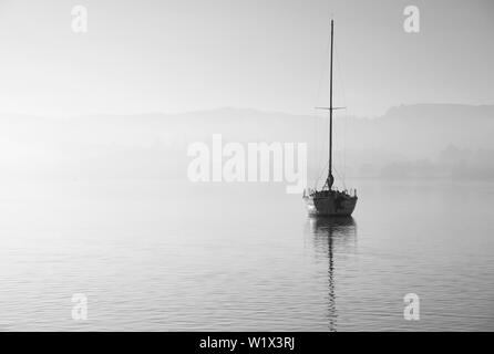 Bellissimo paesaggio unplugged immagine di yacht a vela seduto ancora nel lago calmo acqua nel distretto del lago durante la pacifica misty Autumn Fall sunrise Foto Stock