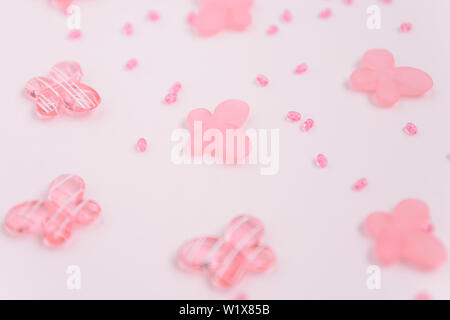 Perline Ovali e butterfly cordoni su un sfondo rosa. Utilizzare come sfondo, carte. Artigianato e accessori hobby Foto Stock