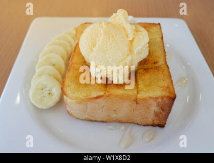 Pane dolce miele santos gelato alla vaniglia con banana frutto su piastra bianca nella caffetteria cafe Foto Stock