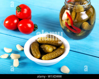 Decapati cetrioli piccoli nella ciotola e jar su sfondo di legno Foto Stock