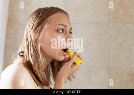 Giovane bella bionda ragazza caucasica con labbro di protezione maker Foto Stock