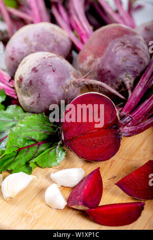 La barbabietola rossa con herbage foglie verdi su sfondo di legno Foto Stock