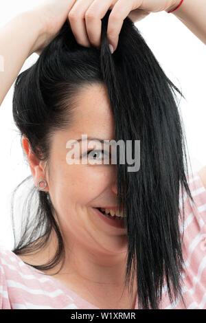 Ritratto di donna felice che copre metà faccia con capelli scuri closeup isolato su bianco di sfondo per studio Foto Stock