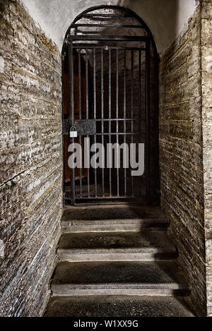 La vecchia porta in acciaio grata nel muro di pietra Foto Stock