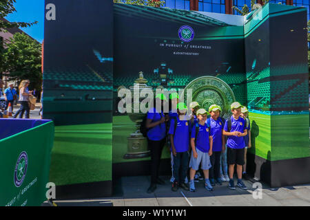 Il torneo di Wimbledon di Londra, Regno Unito. 4 Luglio, 2019. Un gruppo di yung studenti pongono di fronte alla Wimbledon tophies visualizzati in Wimbledon Town Center in un giorno caldo come le temperature sono attesi per raggiungere 27gradi celsius . Credito: amer ghazzal/Alamy Live News Foto Stock