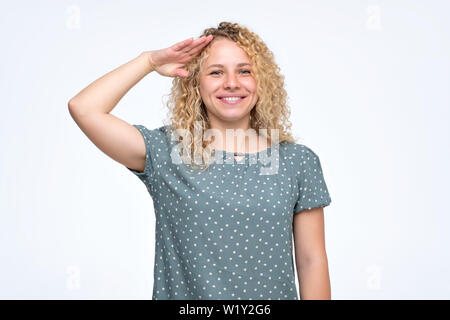 Donna con capelli ricci guardando la fotocamera con salute e pronto a fare ordine Foto Stock