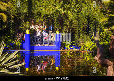 Visitatori guardare un laghetto nel Jardin Majorelle Giardino botanico di Marrakech Foto Stock