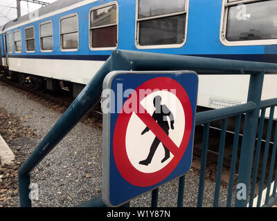 Indicazioni per il divieto di camminare per la via, il treno è in piedi sulle piste in background. Foto Stock