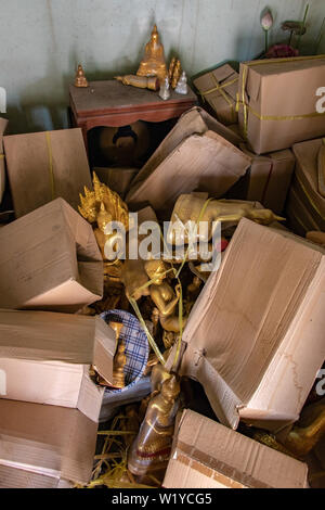 La stanza di deposito con il disordine di una pila di scatole peper e oggetti sacri inclusa la statue di Buddha nel tempio buddista, Thailandia. Foto Stock