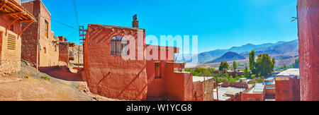 Panorama del villaggio Abyaneh dalla sua strada collinare con vista su vecchi edifici di argilla e Karkas montagne sullo sfondo, l'Iran. Foto Stock