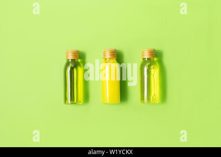 Piatto di laici di tre piccoli mockup bottiglie con spa prodotti cosmetici su sfondo verde. Le donne di bellezza e un salone di bellezza cosmetici concetto. Concetto di eco. Foto Stock