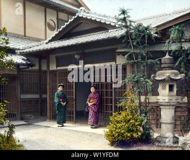 [ 1930 Giappone - ingresso di una casa Giapponese ] - due donne in kimono stand all'ingresso, chiamato genkan, di una casa di quello che sembra essere un bene-a-fare famiglia. Vi è un enorme lanterna di pietra e la grande area aperta di fronte all'ingresso suggerisce molto spazio tra l'ingresso e la porta. Xx secolo vintage vetrino di vetro. Foto Stock