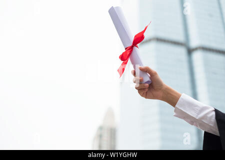 Mano azienda certificato di laurea con sollevata con successo Laurea di università Foto Stock