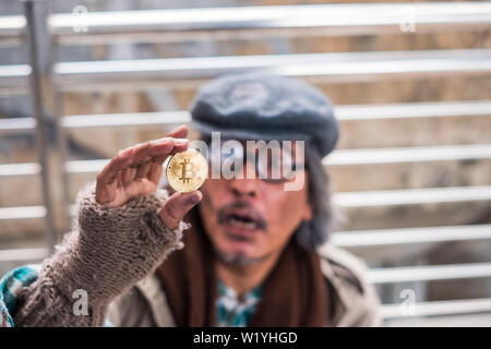 Old Dirty senzatetto azienda golden bitcoin con guardando eccitato Foto Stock