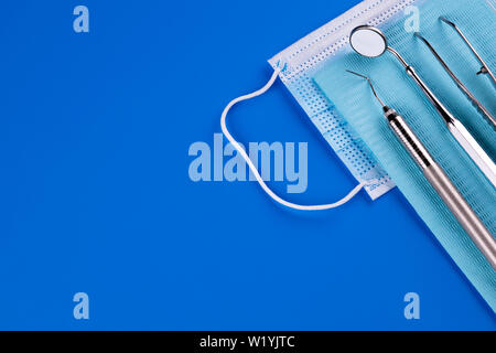 Gli strumenti del dentista attrezzature mediche isolato su sfondo blu in studio dentistico. Specchio dentale, sonda e pinzette.- Immagine Foto Stock