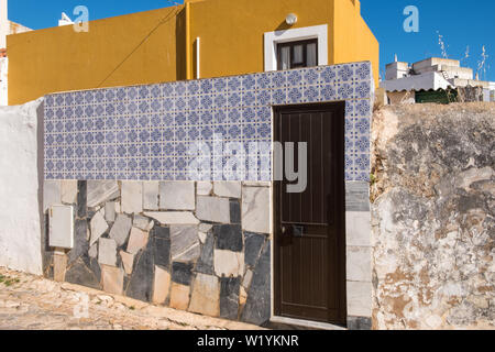 Nella parete anteriore della piccola casa coperto di lastre di marmo e piastrelle decorative in Alvor, Algarve, PORTOGALLO Foto Stock
