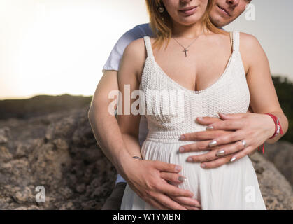 Uomo con la pancia di sua moglie incinta. Donna incinta e amorevole marito abbracciando la pancia sulla spiaggia. Foto Stock