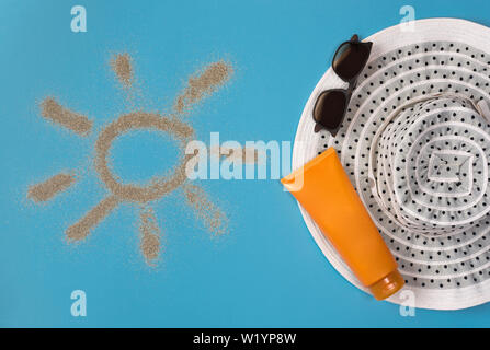 Dipinto di sun, cappello, crema solare e occhiali da sole su sfondo blu. Vista dall'alto. Tema la spiaggia su sfondo blu. Foto Stock