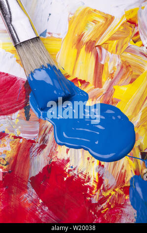Primary colori acrilici su una tavolozza sporca con una spatola e spazzole Foto Stock