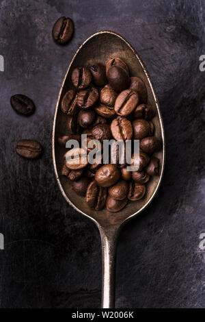 Primo piano di un cucchiaio colmo di tostatura del caffè in grani Foto Stock