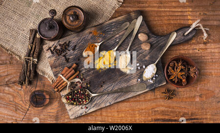 Miscelati aromi e spezie di colore scuro sul tagliere di legno Foto Stock
