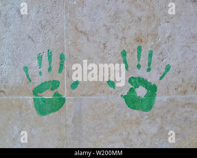 Handprints verde sulla parete di piastrelle in marmo di close-up. Foto Stock
