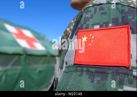 Feldkirchen, Germania. 04 Luglio, 2019. La bandiera della Repubblica popolare cinese è cucita sulla uniforme di un soldato del popolo cinese della Esercito di liberazione. Medical soldati del popolo cinese della Esercito di Liberazione hanno avviato un esercizio con la Bundeswehr in Baviera. Fino al 17 luglio, lo scenario di una comune missione ONU saranno addestrati a Feldkirchen nella Bassa Baviera. Credito: Armin Weigel/dpa/Alamy Live News Foto Stock