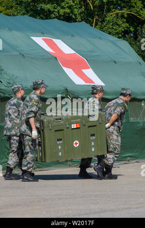 Feldkirchen, Germania. 04 Luglio, 2019. I soldati del popolo cinese della Esercito di Liberazione trasportare una scatola davanti ad un mobile della stazione di salvataggio. Medical soldati del popolo cinese della Esercito di Liberazione hanno avviato un esercizio con la Bundeswehr in Baviera. Fino al 17 luglio, lo scenario di una comune missione ONU saranno addestrati a Feldkirchen nella Bassa Baviera. Credito: Armin Weigel/dpa/Alamy Live News Foto Stock