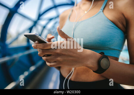 Immagine ritagliata della donna in abbigliamento sportivo tramite telefono cellulare. Focus su mani e smart phone. Foto Stock