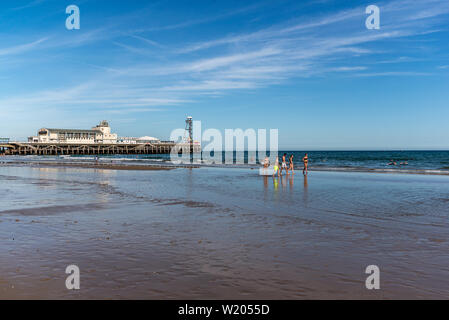 Bournemouth Dorset, Inghilterra, Regno Unito, 4 luglio 2019, meteo: il calore del giorno indugia in prima serata sulla costa sud come un mini ondata di caldo costruisce. Amici godere la calma acqua poco profonda di bassa marea vicino al molo e godervi il caldo d'estate. Credito: Paolo Biggins/Alamy Live Foto Stock