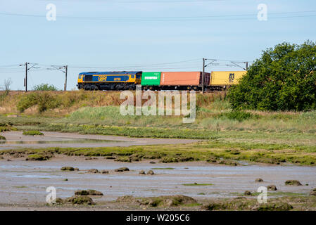 GB classe di merci su rotaie 66 diesel locomotiva elettrica trasporta un contenitore treno merci sulla costa est la linea di maggiore Anglia stazione ferroviaria nei pressi di Manningtree Foto Stock