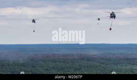 Alt Jabel, Germania. 04 Luglio, 2019. Tre elicotteri della Bundeswehr tipo NH90 con spegnimento serbatoi di acqua di sorvolare una foresta vicino Alt Jabel e scarico di acqua di spegnimento più isolate macchie di fuoco (vista aerea da un elicottero). La situazione nella foresta zona incendio su una ex zona di addestramento militare vicino Lübtheen nel Meclemburgo-Pomerania Occidentale ha attenuato leggermente per la prima volta dallo scoppio dell'incendio. I primi abitanti furono in grado di tornare alle loro case che era stata cancellata come una precauzione. Credito: Jens Büttner/dpa-Zentralbild/dpa/Alamy Live News Foto Stock