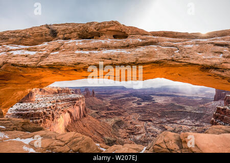 Visualizzazione classica del famoso Mesa Arch, simbolo del sud-ovest americano, illuminata a scenic golden. La luce del mattino al sorgere del sole su una bella giornata invernale in Foto Stock