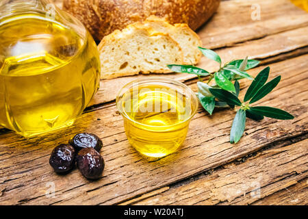 Organico, sana e naturale pressato a freddo Olio di oliva su un tavolo di legno. Virgin italiano o spagnolo di olio di oliva in una ciotola per una sana prima colazione Foto Stock