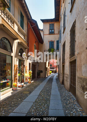 Stretta strada di ciottoli con negozi nel villaggio di Orta San Giulio italia un pomeriggio estivo Foto Stock