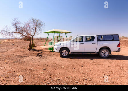 Toyota Hilux pick-up truck fermato accanto a un picnic in calcestruzzo di tavolo e panche con una tettoia per ombra, tipicamente collocato ogni 10-20km lungo le strade in Foto Stock