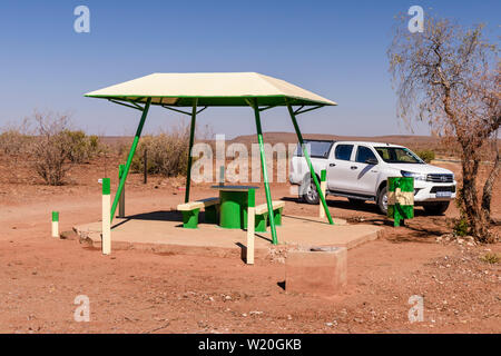 Toyota Hilux pick-up truck fermato accanto a un picnic in calcestruzzo di tavolo e panche con una tettoia per ombra, tipicamente collocato ogni 10-20km lungo le strade in Foto Stock