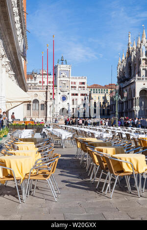 Le tabelle di cui pronto per il pranzo in Piazetta San Marco, Venezia, Veneto, Italia con una vista verso la Torre dell Orologio e Basilica con la folla di turisti sightse Foto Stock