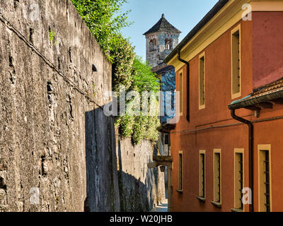 Strada desolata con via e pareti di pietra sull'Isola di San Giulio nel Lago d'Orta con il campanile di San Giulio Basilica in background durante una Foto Stock