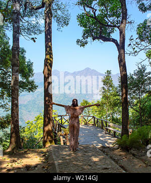 Donne alzando le braccia e gli alberi di sfondo e montagne a Nern Chang Puak punto di vista , Kanchanaburi, Thailandia. Foto Stock