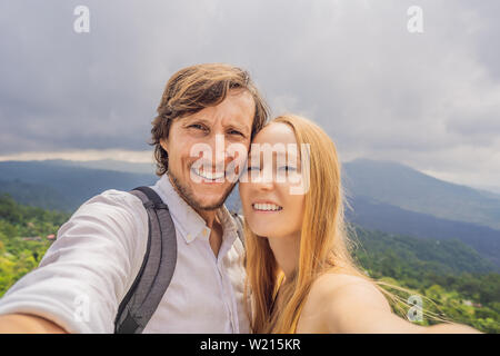 Uomo e donna che fa selfie sullo sfondo del vulcano Batur e Agung mountain view al mattino da Kintamani, Bali, Indonesia Foto Stock