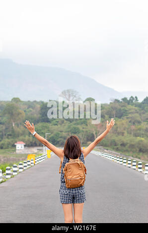 Donne sollevare le braccia e la spalla zaino montagne sullo sfondo di Wang Bon dam ,Nakhon Nayok in Thailandia. Foto Stock