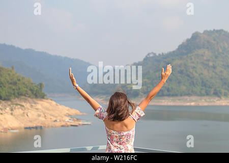 Donne alzando le braccia e sullo sfondo le montagne e acqua a Khun Dan Prakan Chon Dam ,Nakhon Nayok in Thailandia.